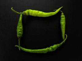 Natural green chilies on a dark background. Top view with food background, black stone table, copy space. photo