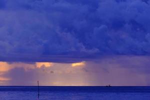 Rain from gray clouds on ocean at dusk photo