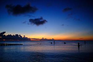 Standup paddleboarders return at sunset photo