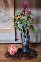 Purple and yellow flowers in vase next to cloth ball in traditional Japanese home photo