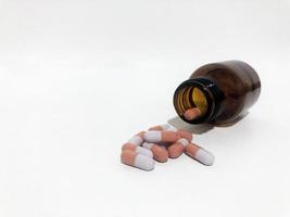 las píldoras o tabletas de medicina caen y salen de la botella de plástico blanco. foto