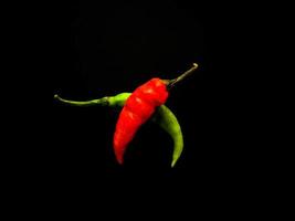 Natural green and red chilies on a dark background. Top view with food background, black stone table, copy space. photo