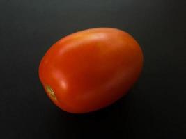 Natural tomatoes on a dark background. Top view with food background, black stone table, copy space. photo