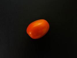 Natural tomatoes on a dark background. Top view with food background, black stone table, copy space. photo