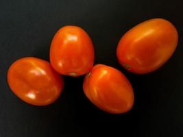 Natural tomatoes on a dark background. Top view with food background, black stone table, copy space. photo
