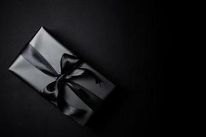 Top view of black gift box with black ribbons isolated on black background. photo