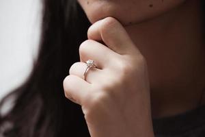 Cerca de un elegante anillo de diamantes de compromiso en el dedo de la mujer foto