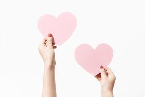 Close up women holding pink blank  paper with heart shape on white background. photo