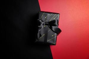 black gift box with black ribbons isolated on black background photo