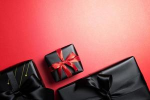 vista superior de la caja de regalo negra con cintas rojas y negras aisladas en el fondo rojo. foto