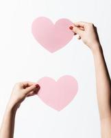 Close up women holding pink blank  paper with heart shape on white background. photo