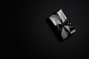 Top view of black gift box with black ribbons isolated on black background. photo