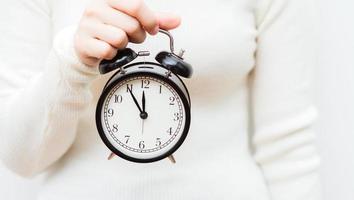 Close up shot of female hands holding a small clock. photo