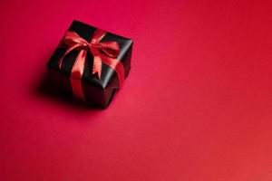 Top view of black gift box with red and black ribbons isolated on red background. photo