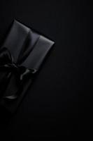 vista superior de la caja de regalo negra con cintas negras aisladas sobre fondo negro. foto