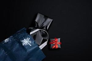 Top view of black gift box with red and black ribbons isolated on black background. photo