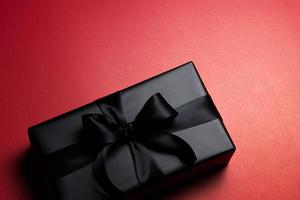 Top view of black gift box with red and black ribbons isolated on red background. photo