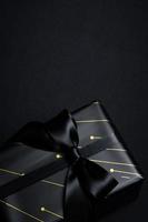 Top view of black gift box with black ribbons isolated on black background. photo