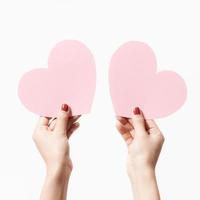 Close up women holding pink blank  paper with heart shape on white background. photo