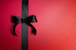 Top view of black ribbon on red background with free copy space for text. photo