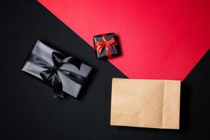 Top view of black gift box with red and black ribbons isolated on black background. photo