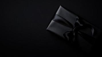 Top view of black gift box with black ribbons isolated on black background. photo