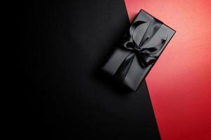 black gift box with black ribbons isolated on black background photo