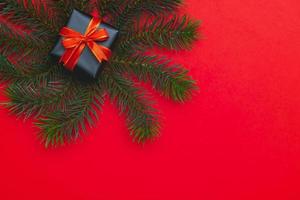 Top view of Christmas gift box red balls with spruce branches, pine cones, red berries and bell on red background. photo