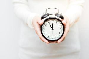 Close up shot of female hands holding a small clock. photo