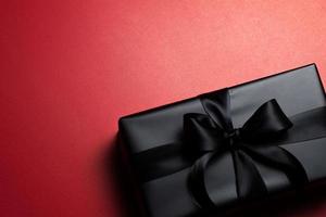 Top view of black gift box with red and black ribbons isolated on red background. photo