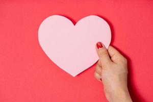 Close up women holding pink blank paper with heart shape on white background. photo