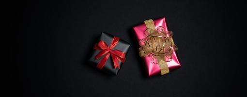 Top view of black gift box with red and black ribbons isolated on black background. photo