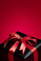 Top view of black gift box with red and black ribbons isolated on red background. photo