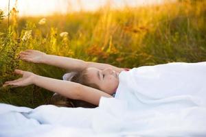 Girl sleeps on bed in grass, Sweet stretches and yawns sleepily, good morning in fresh air. Eco-friendly, healthy sleep, Protection from mosquitoes, clean nature, ecology, children's health photo