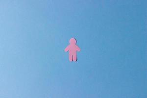 The silhouette of a man carved from pink paper on a blue background photo