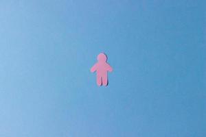 The silhouette of a man carved from pink paper on a blue background photo