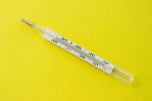 Mercury thermometer on a yellow background. Single object photo