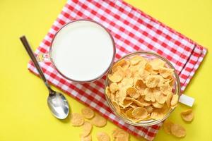 tazón de copos de maíz desayuno y merienda para un concepto de comida saludable, desayuno matutino cereal integral fresco, copos de maíz con leche sobre fondo amarillo - vista superior foto