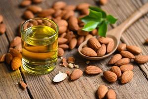 Almond oil and Almonds nuts on wooden, Delicious sweet almonds oil in glass, roasted almond nut for healthy food and snack organic vegetable oils for cooking or spa photo