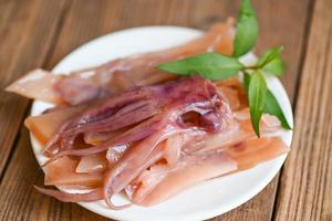 pickled squid on white plate, raw squid for cooking food on wooden table, preserving food seafood photo