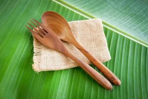 Wooden spoon and fork kitchenware set on sack banana leaf background Zero waste use less plastic concept photo