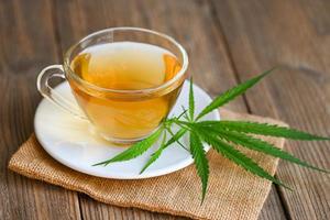 Cannabis tea herbal on tea cup with cannabis leaf marijuana leaves herb on wooden background, health tea with hemp leaf plant THC CBD herbs food and medical photo