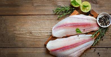 fresh raw pangasius fish fillet with herb and spices black pepper lemon lime, fish fillet on wooden board with ingredients for cooking, meat dolly fish tilapia striped catfish photo
