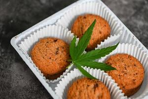 Cannabis food cookies box with cannabis leaf marijuana herb on dark background, delicious sweet dessert cookie with hemp leaf plant THC CBD herbs food snack and medical photo