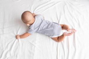 Top view and  baby in a striped shirt is crawling on a white carpet. photo