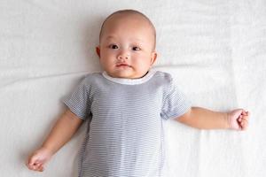 niño sonriente con una camisa a rayas con un puñado de manos sobre un colchón blanco foto