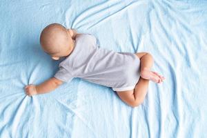 Top view and  baby in a striped shirt is crawling on a white carpet. photo