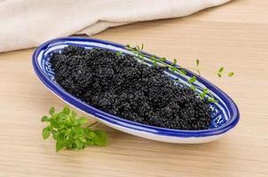 Black caviar in a bowl on wooden background photo