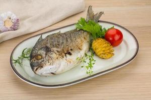 Grilled dorado on the plate and wooden background photo