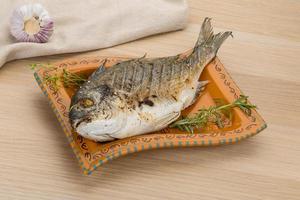 Grilled dorado on the plate and wooden background photo